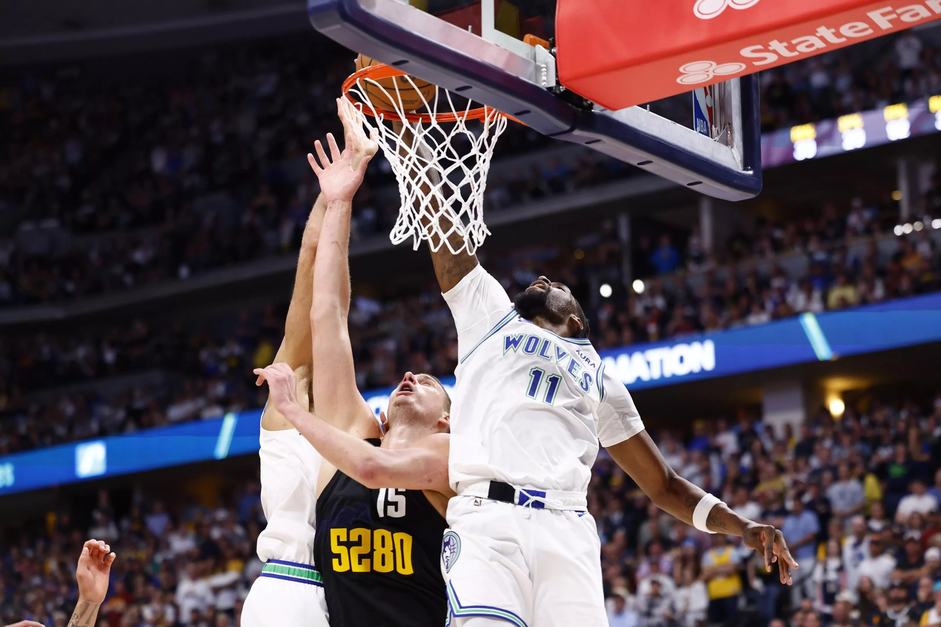 Nikola Jokic attempts a shot against Naz Reid and Minnesota Timberwolves defender