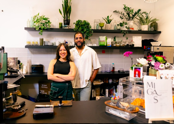 a man and a woman posing behind a counter in front of plans on shelves