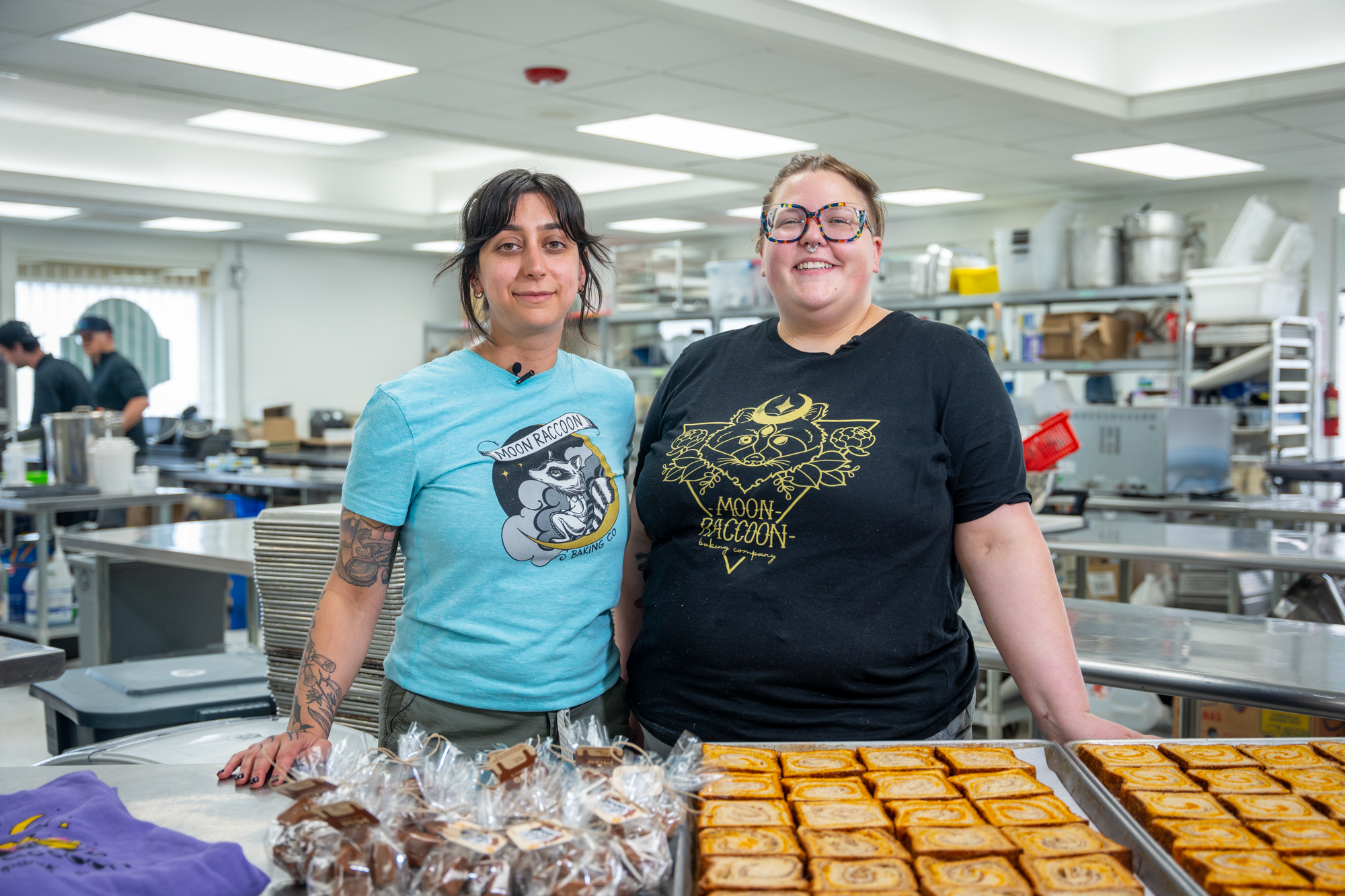 two women posing in front of pastries