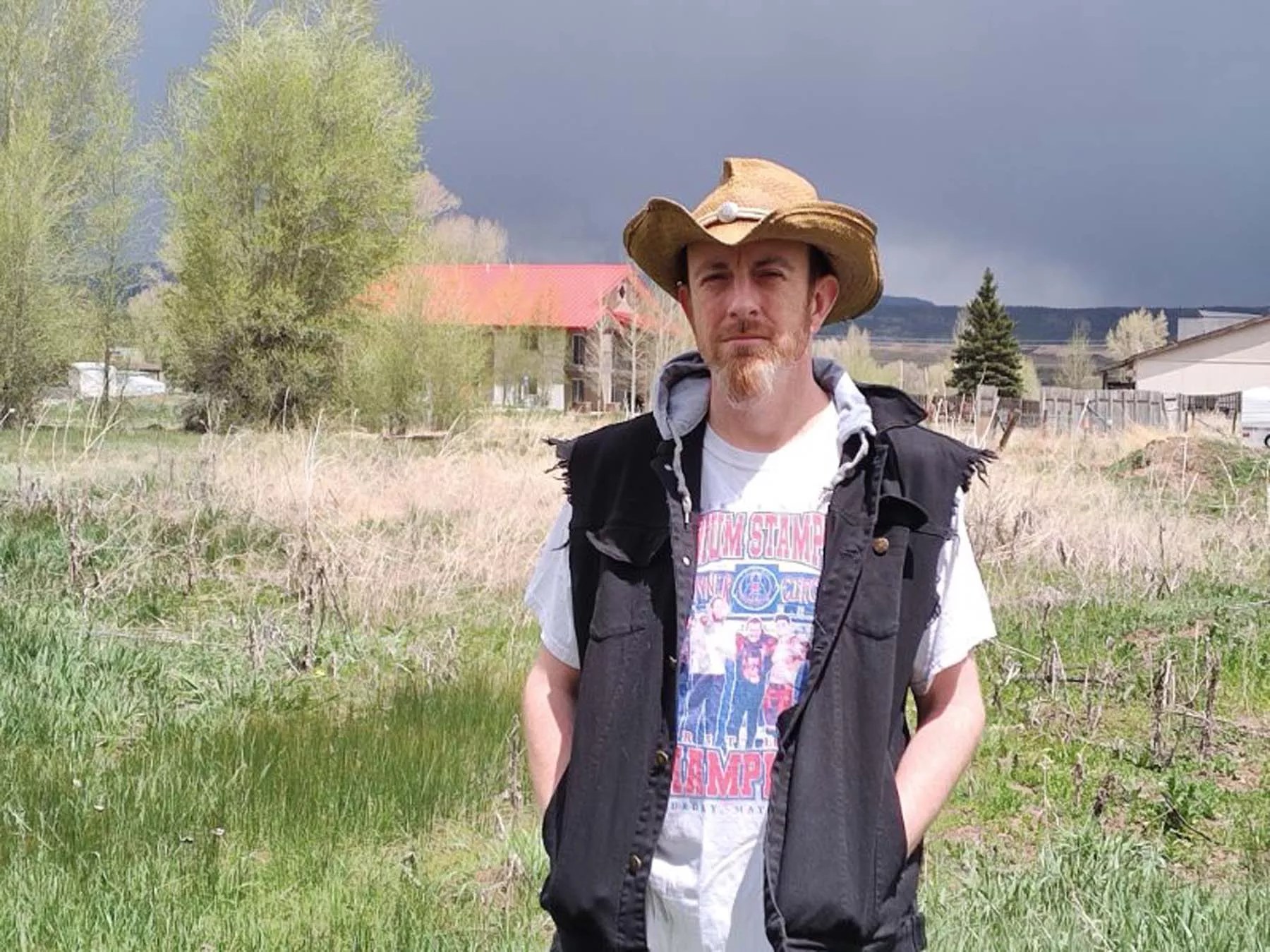 man in vest and hat standing outside