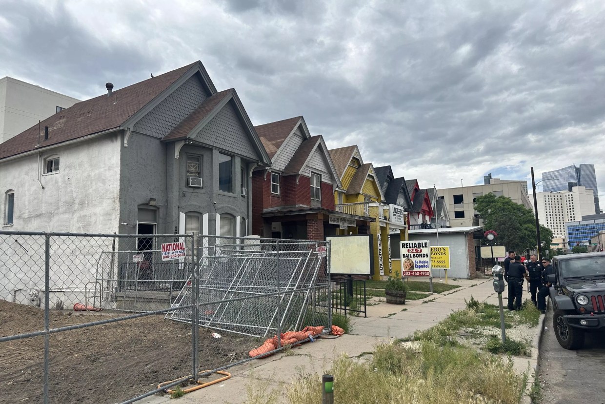 Police stand outside of an abandoned home on bail bond row in Denver