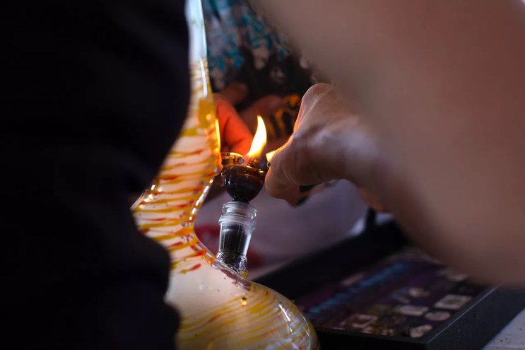Person lights marijuana in a bong bowl