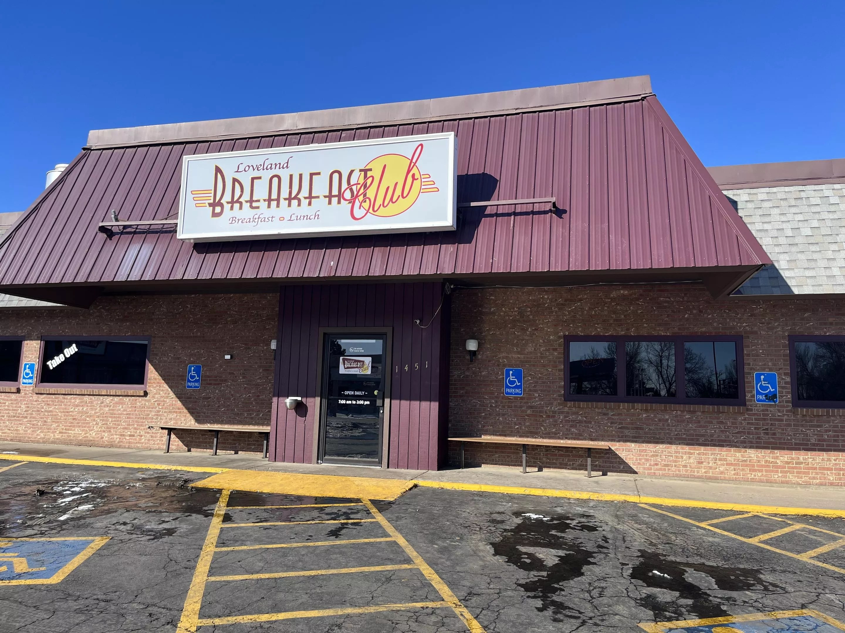 front of a diner with a 'breakfast club" sign
