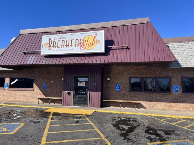front of a diner with a 'breakfast club" sign