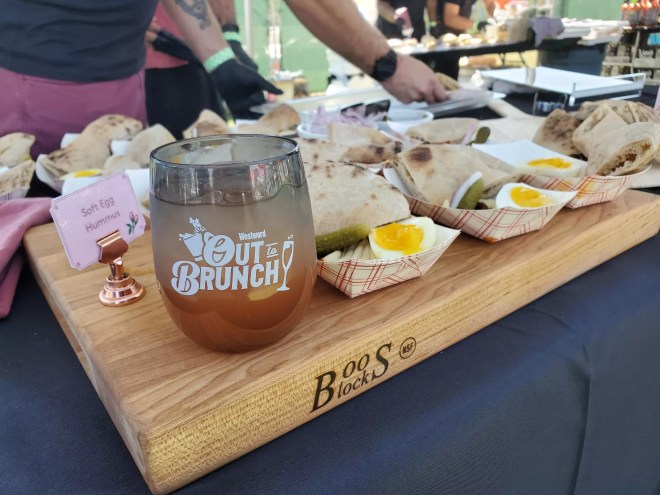 a cup on a cutting board next to samples of hummus