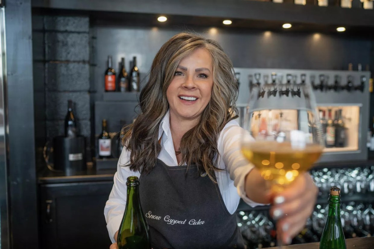 Female cidermaker holding a glass of cider.