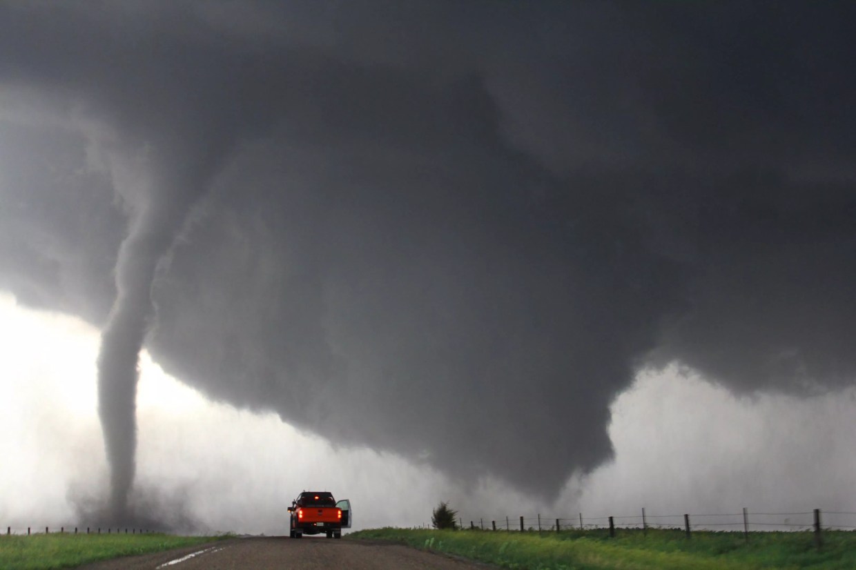 Red pickup truck in front of tornado on road
