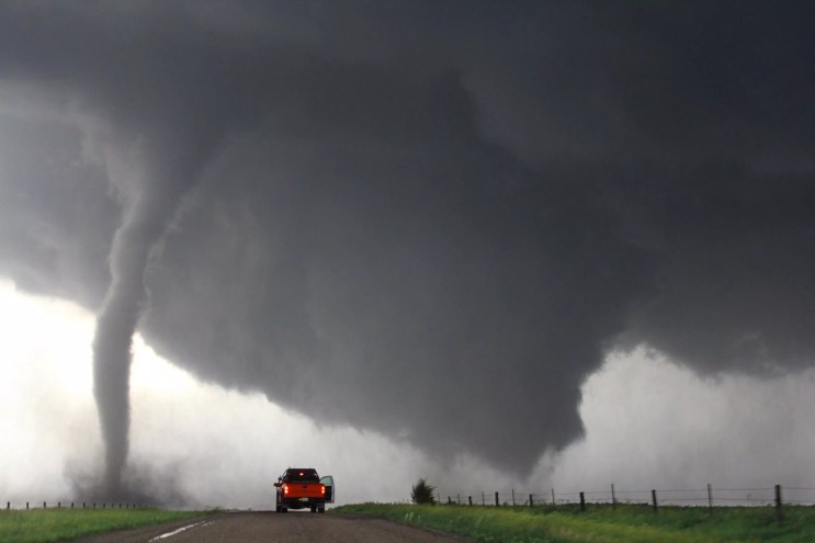 Red pickup truck in front of tornado on road