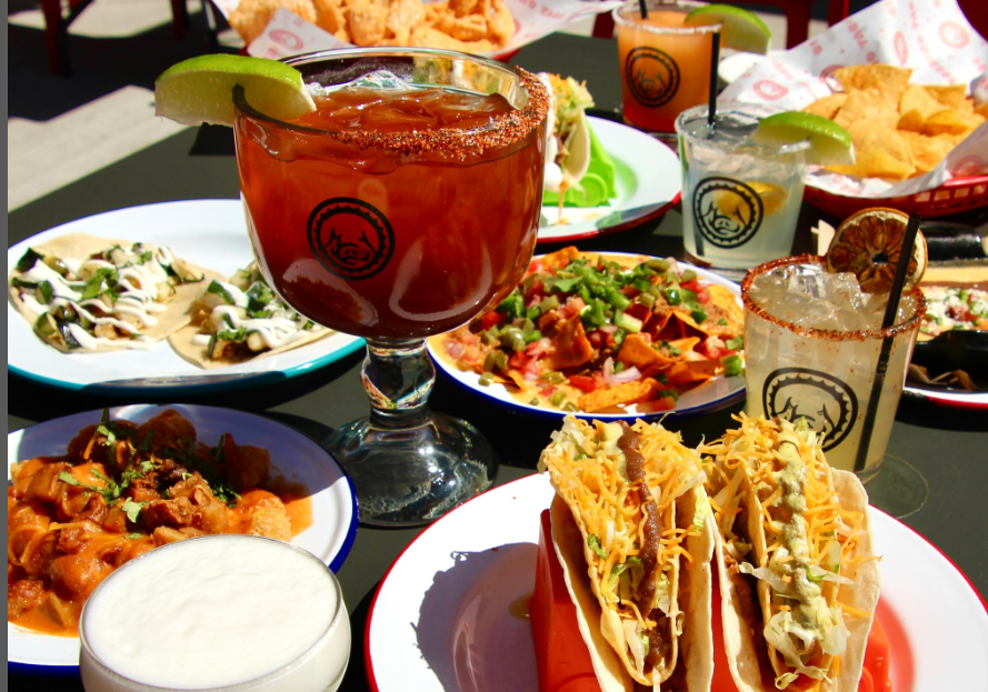 a red drink in a glass surrounded by various food items