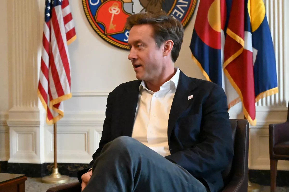 Mayor Mike Johnston man sits next to American flag.