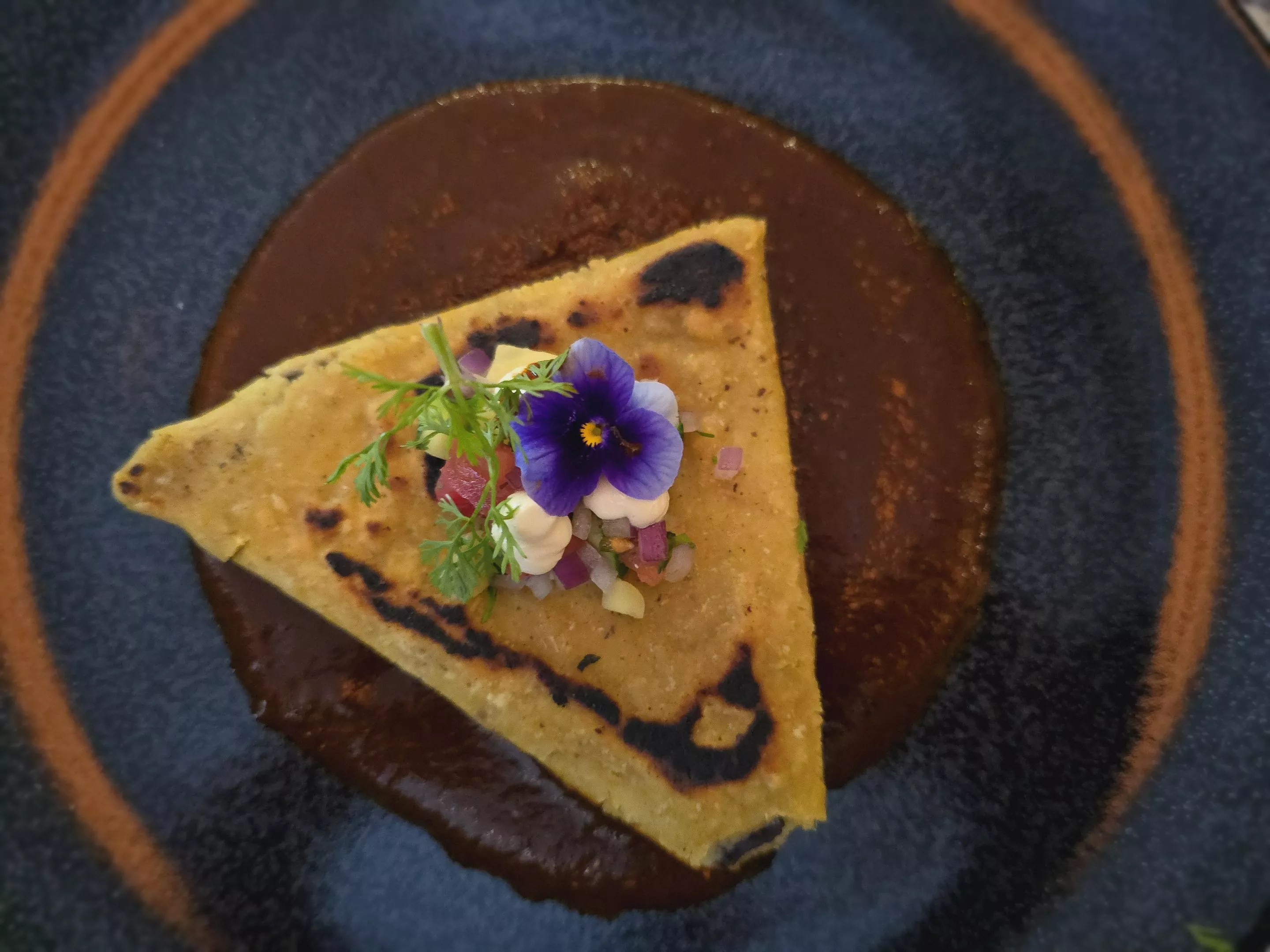 a tetela on a plate over dark sauce