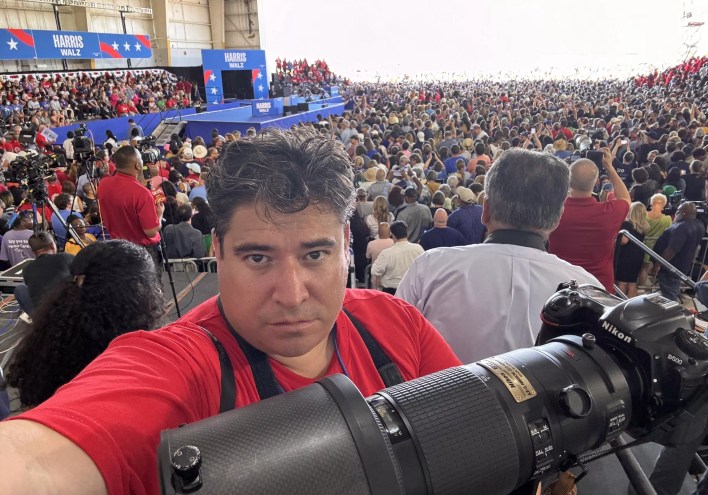 man with camera in front of crowd.