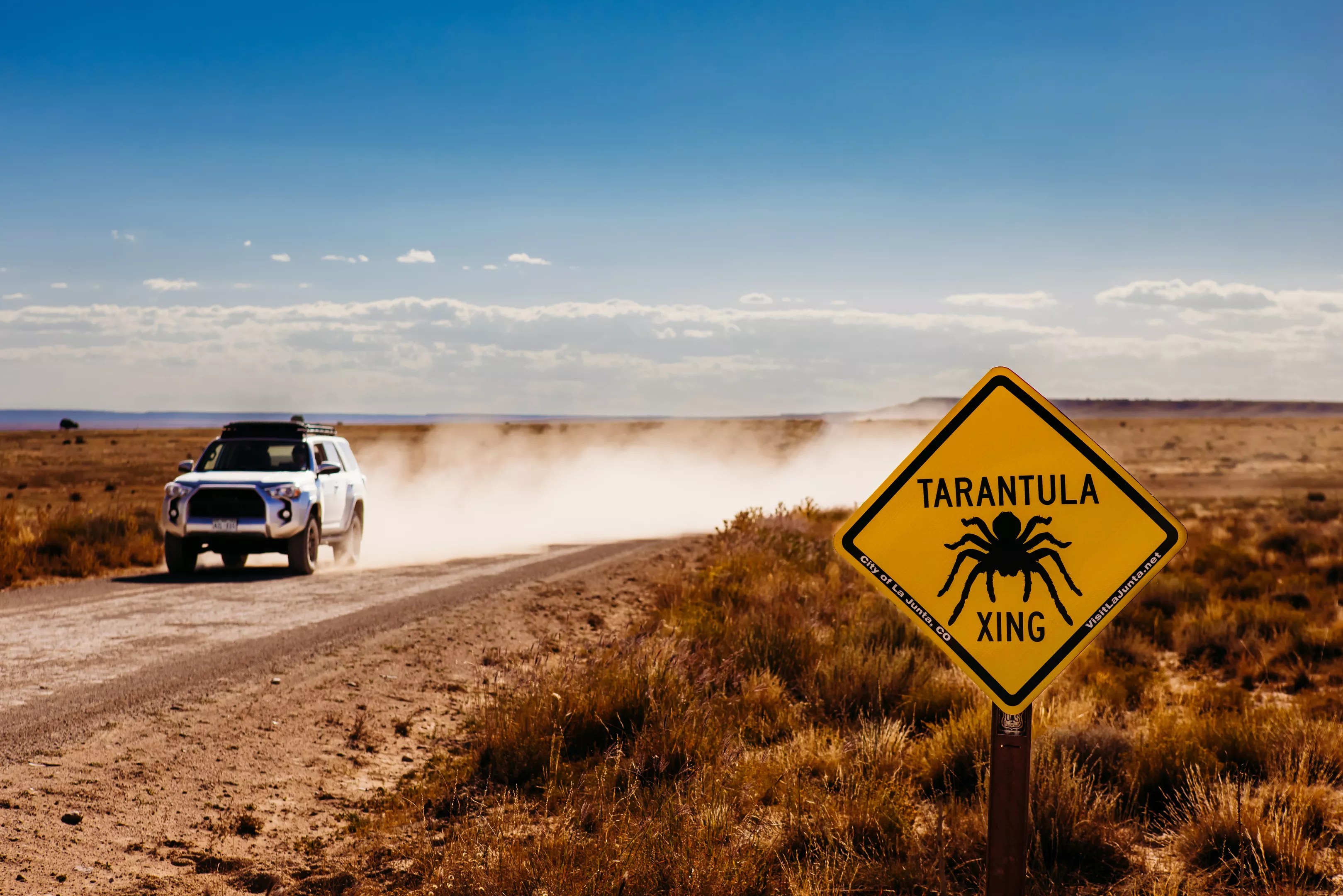 A Toyota 4Runner driving down a dirt road in La Junta, marked by a "tarantula crossing" sign