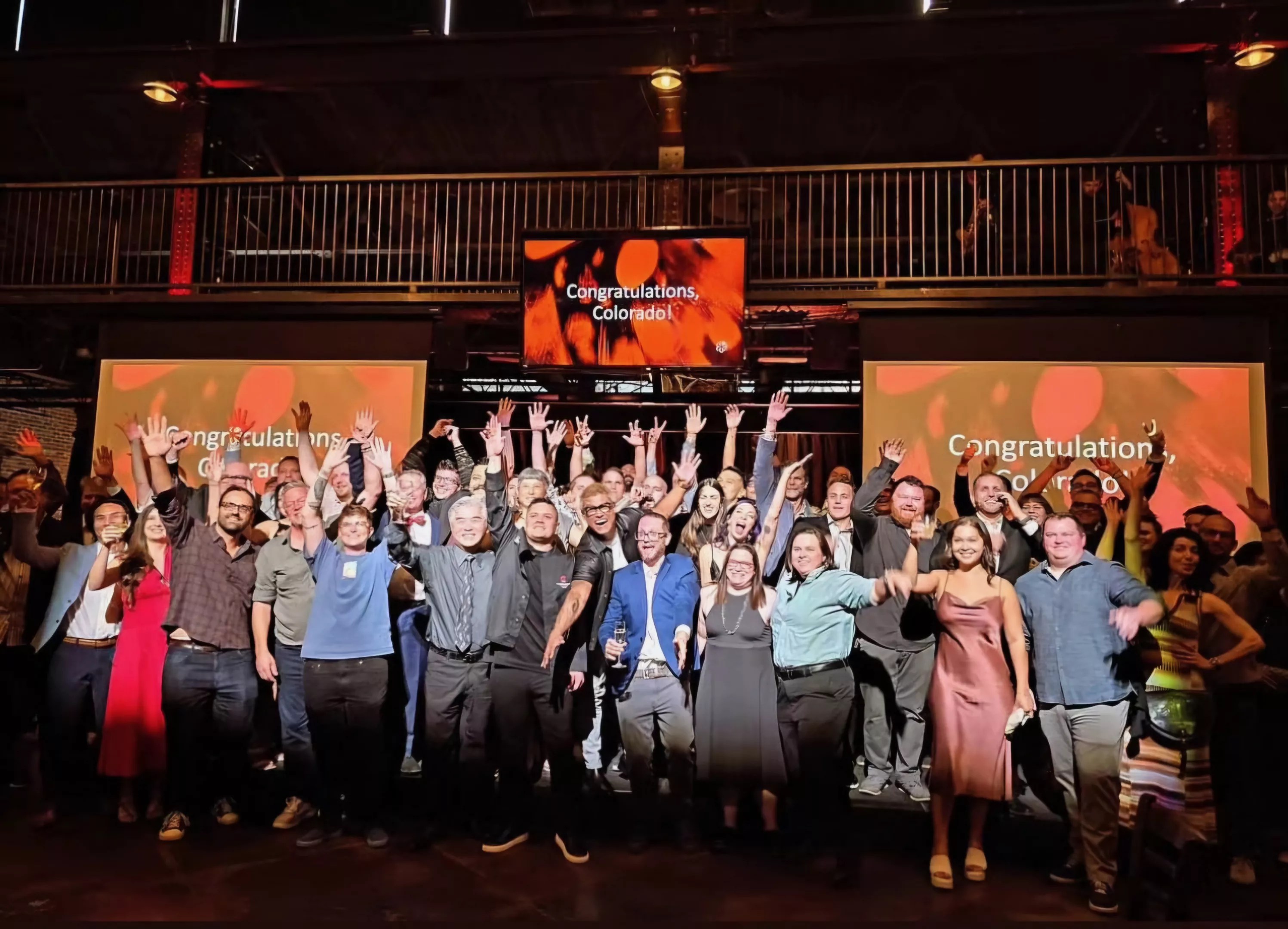 large group of people posing with hands in the air
