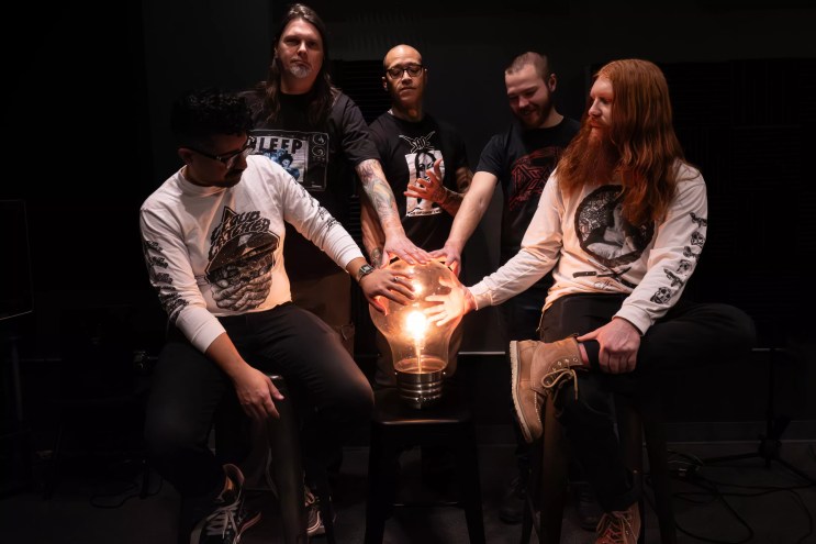 bandmembers gathered around a giant lightbulb
