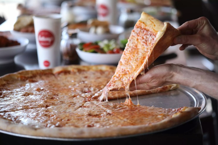 slice being pulled from a cheese pizza