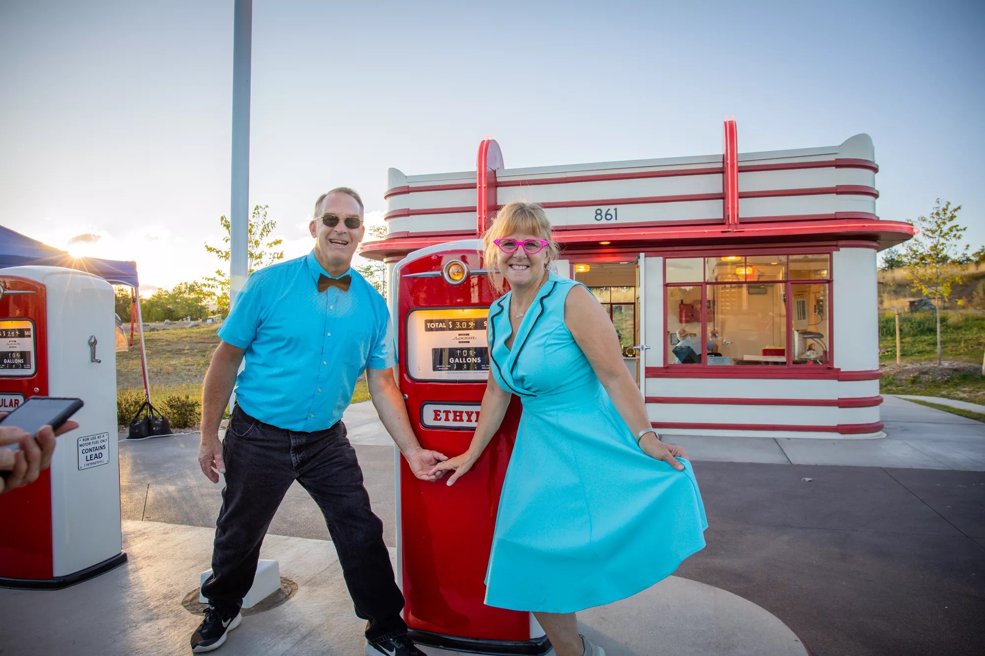 couple poses in front of 1950s gas station