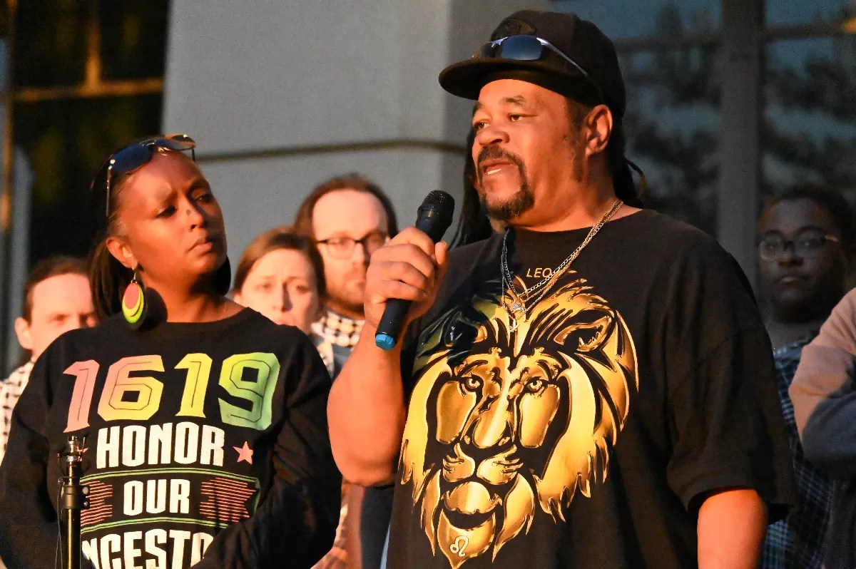 Man with hat speaks on microphone at protest