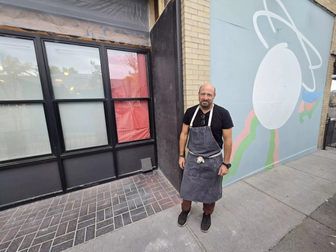 man in an apron standing in front of a building