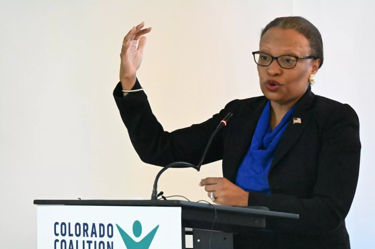 A woman talks with her hand up.