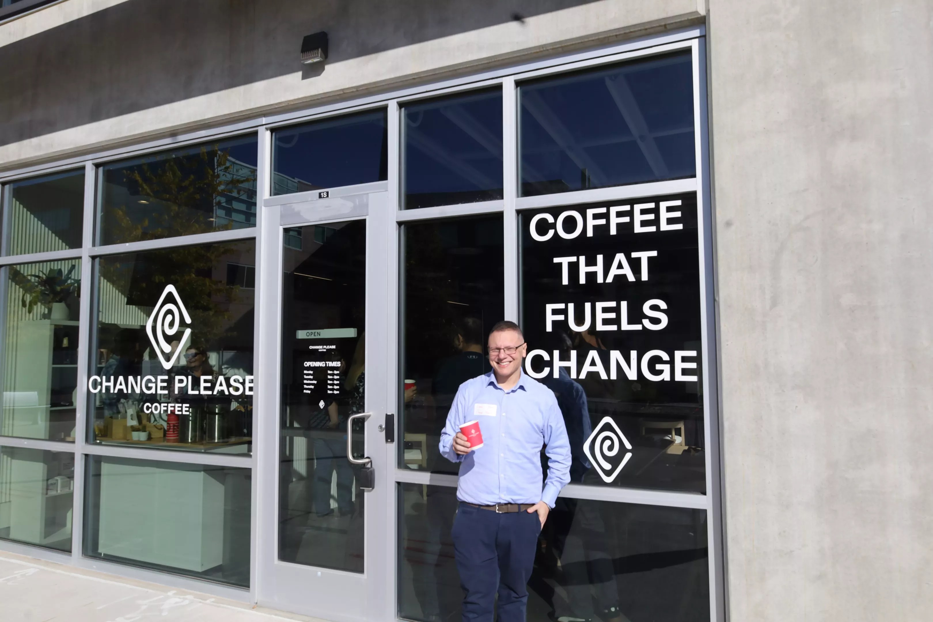 man standing in front of a window that says "coffee that fuels change"