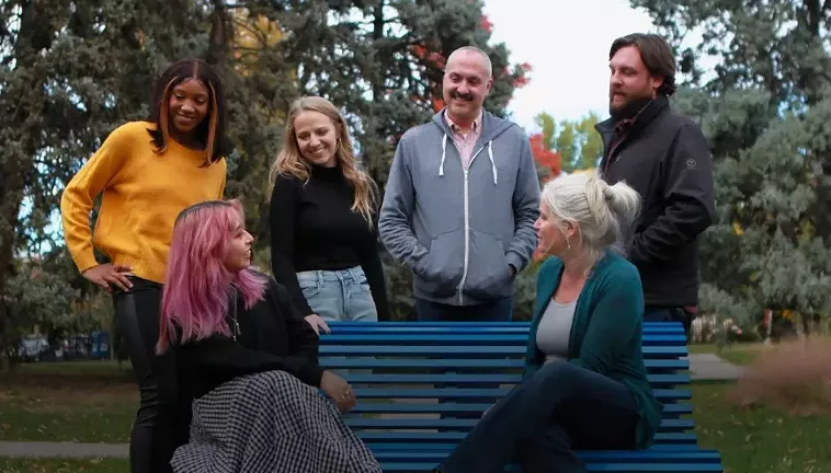 group of people gathered around a blue bench