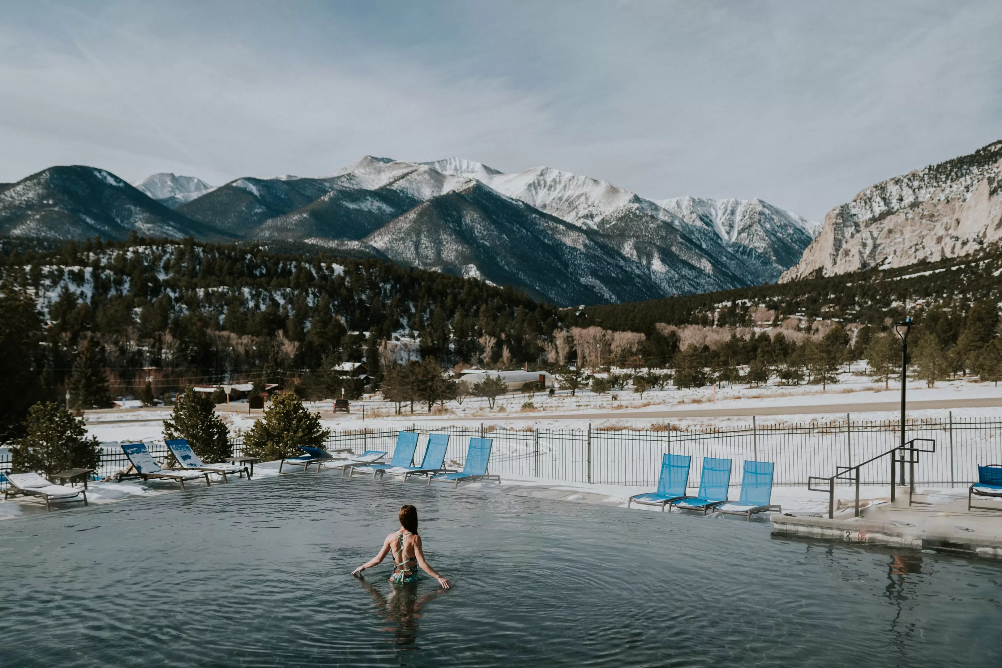 A woman backdropped by snowy mountains while soaking in an infinity pool at Mount Princeton Hot Springs