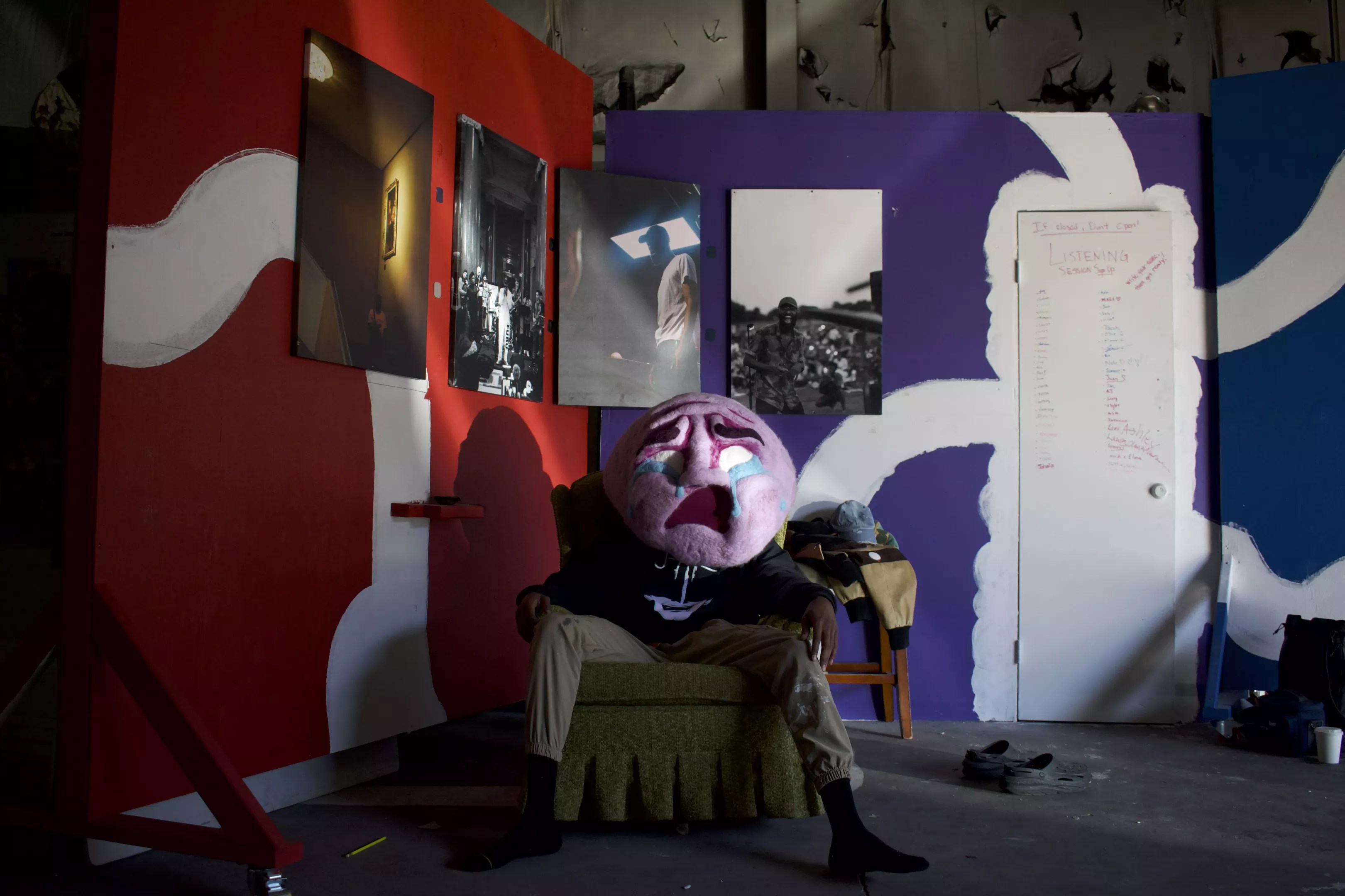 Person in chair with large crying mask.