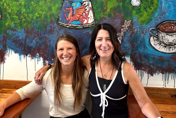 two women posting in front of a mural