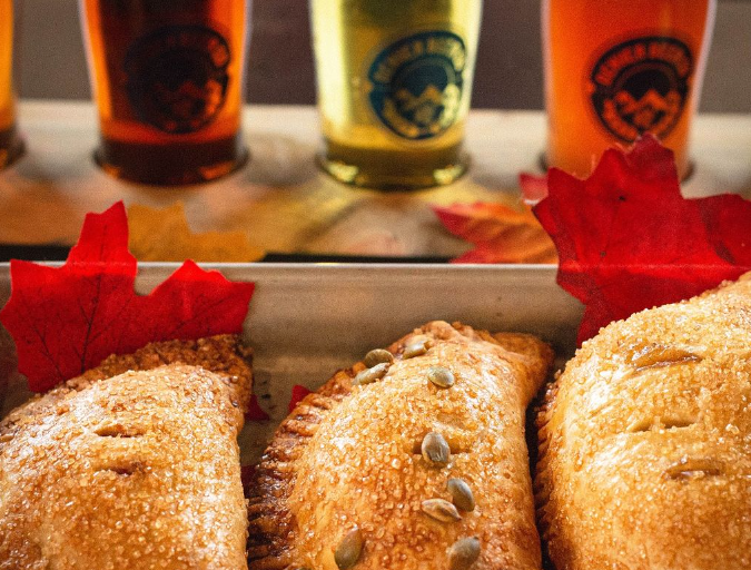 three hand pies in front of three glasses of beer
