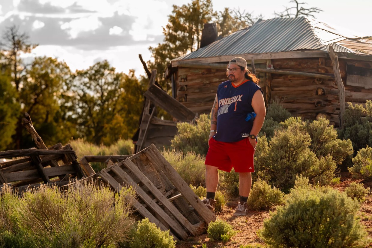 A man dressed in red shorts and a blue shirt stands in a rustic old building.