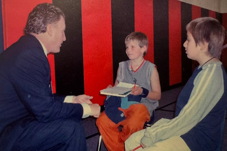Two boys interview a man.