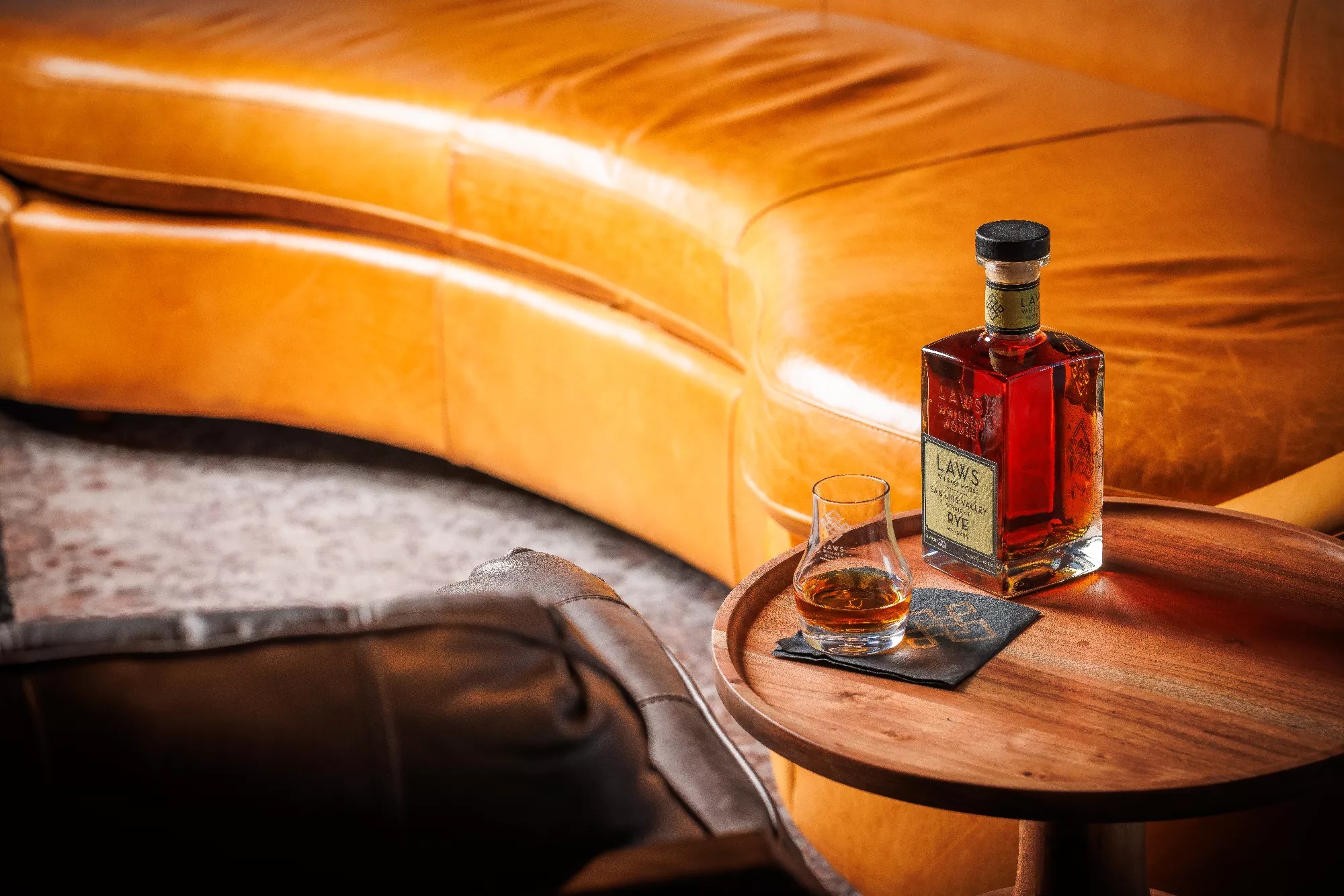 bottle of whiskey next to a leather couch