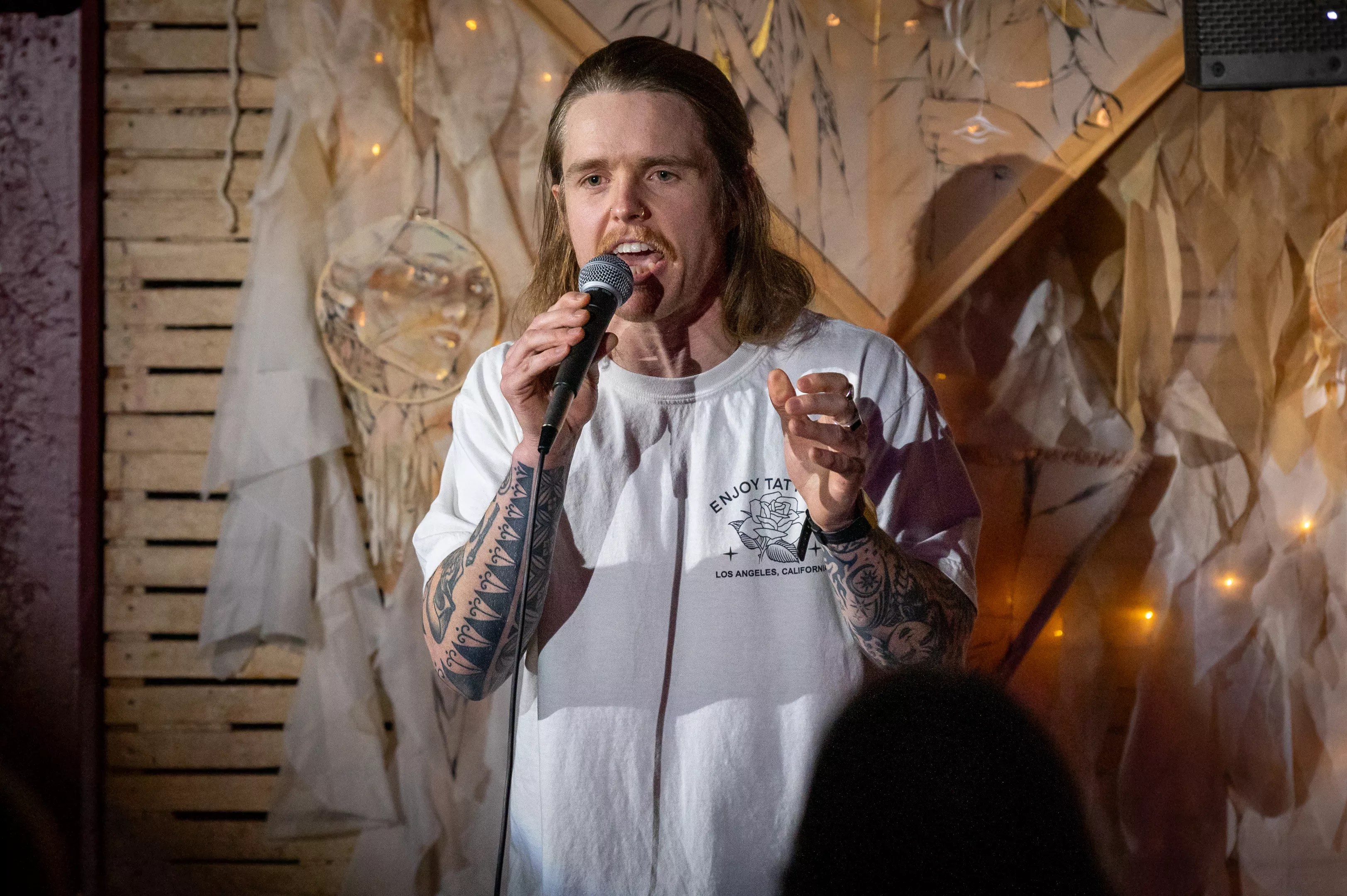 Onstage, a man in white hoodie speaks into a microphone.