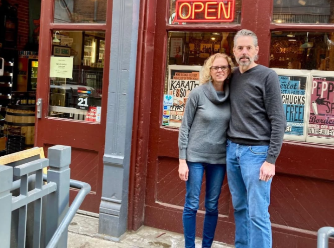 woman and man posing in front of a wine shop