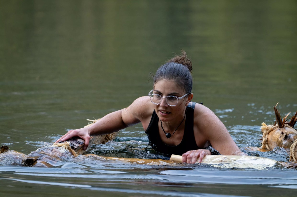 Rose Hyak submerged in water and floating on a primitive raft during a survival challenge
