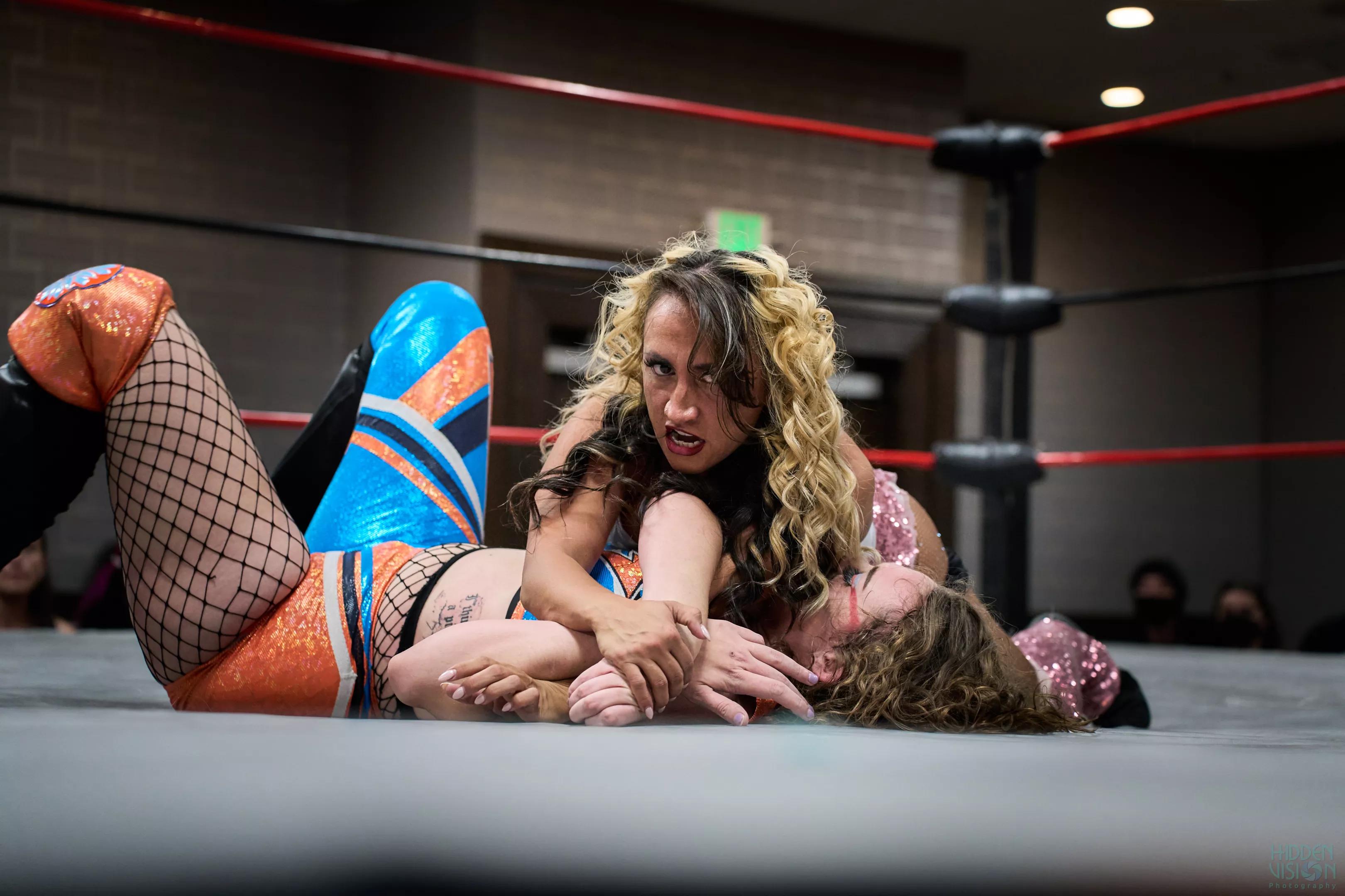 A female wrestler pins down another wrestler