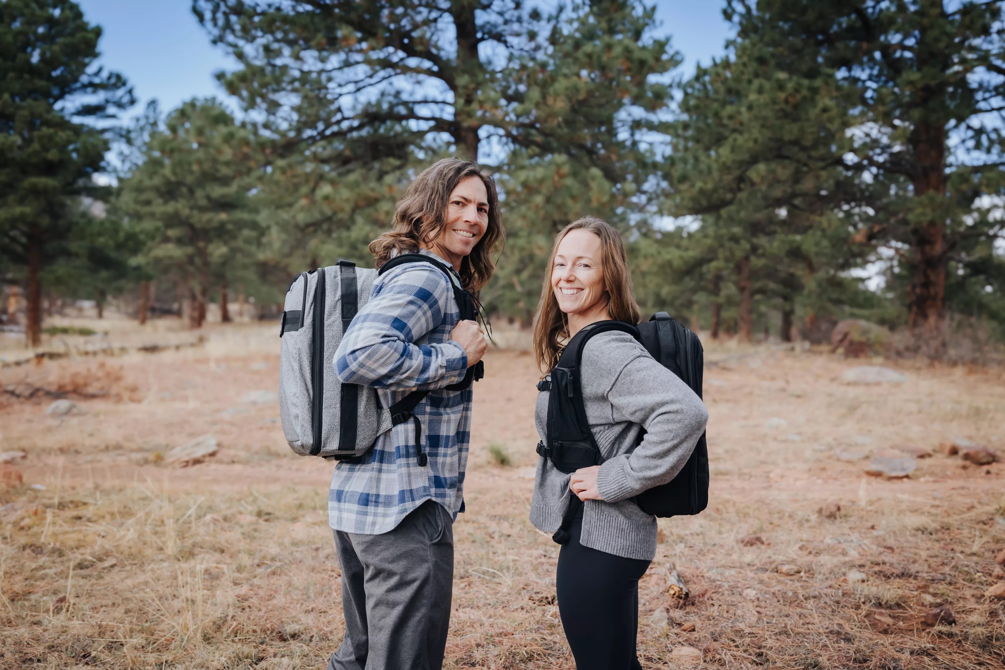 A man and woman show off their backpacks