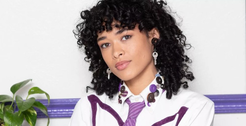 woman with curly black hair in white shirt