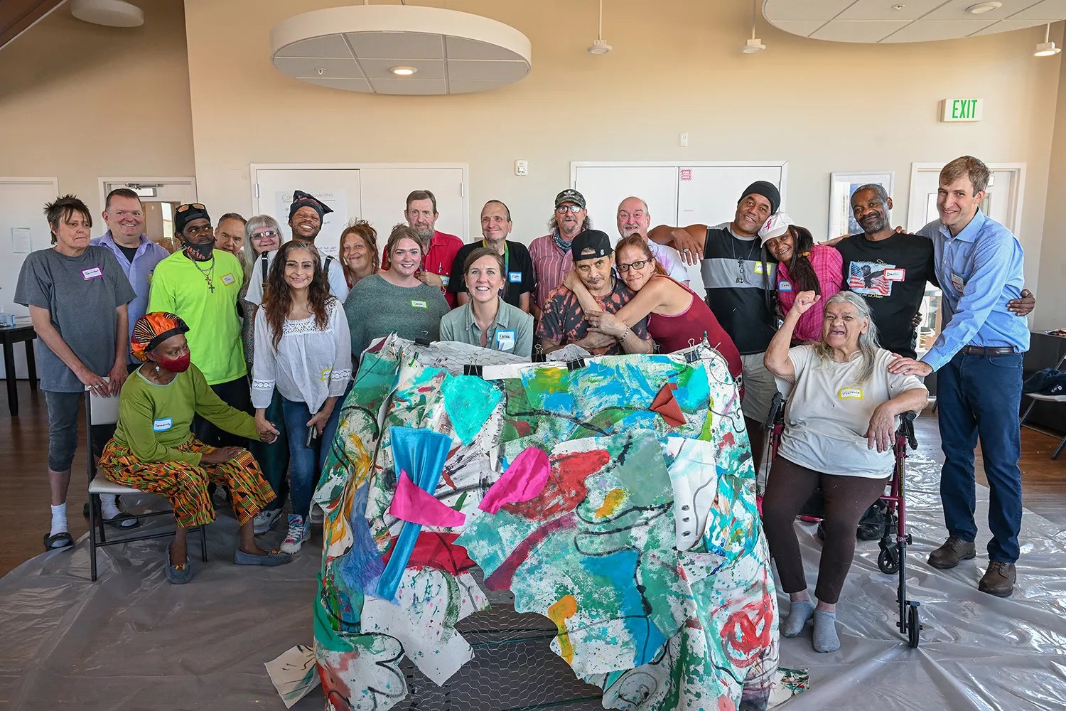 A group of people stands behind a large sculpture.