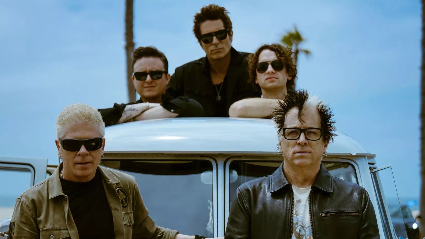 Members of The Offspring pose on a car