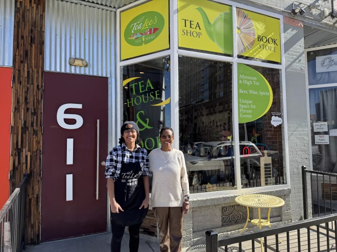 two people standing outside a tea shop