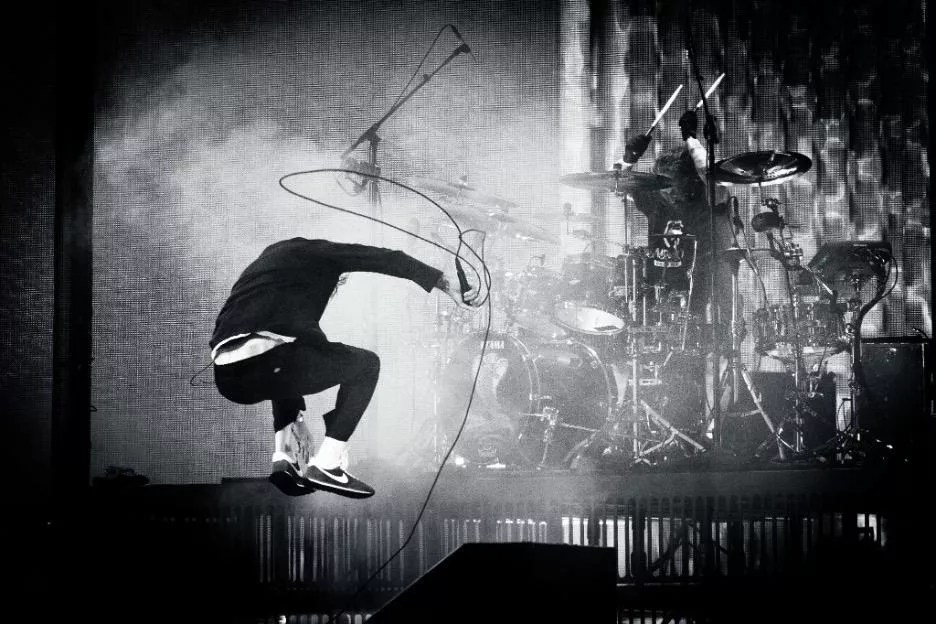 member of Deftones jumping on stage with a microphone
