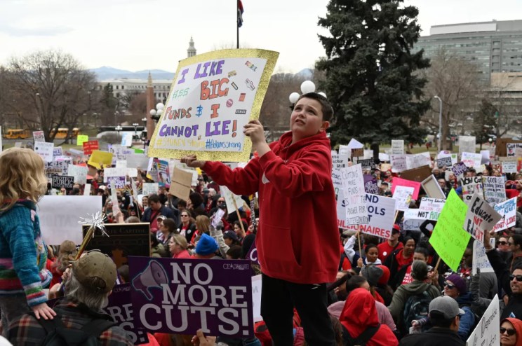 A kid raises a sign.