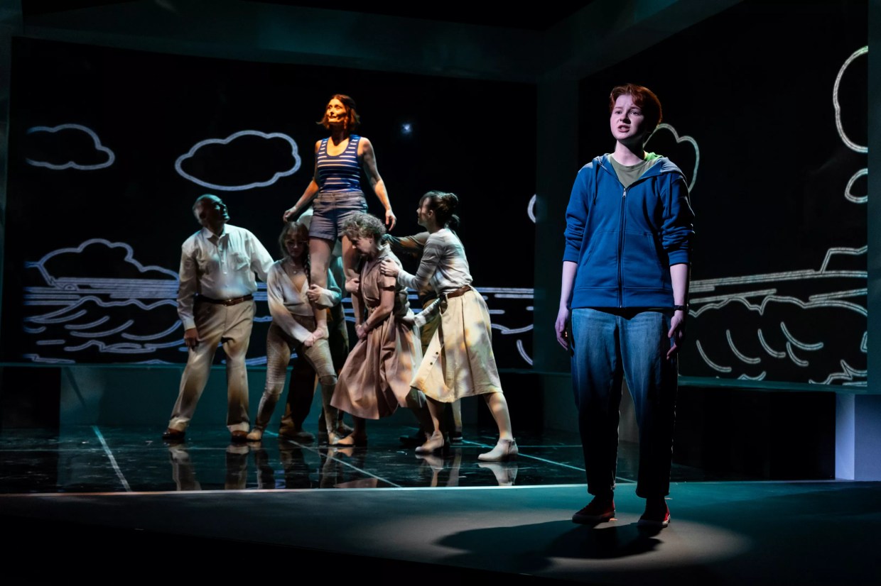 A boy stands while a woman is raised by a crowd behind him.