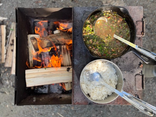 food in pots being cooked by a fire