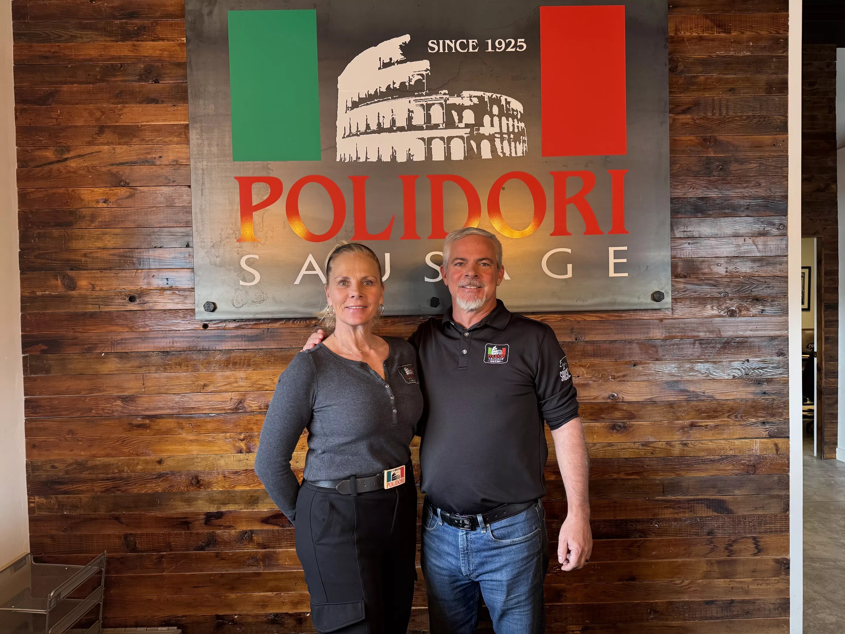 woman and man in front of a "polidori" sign