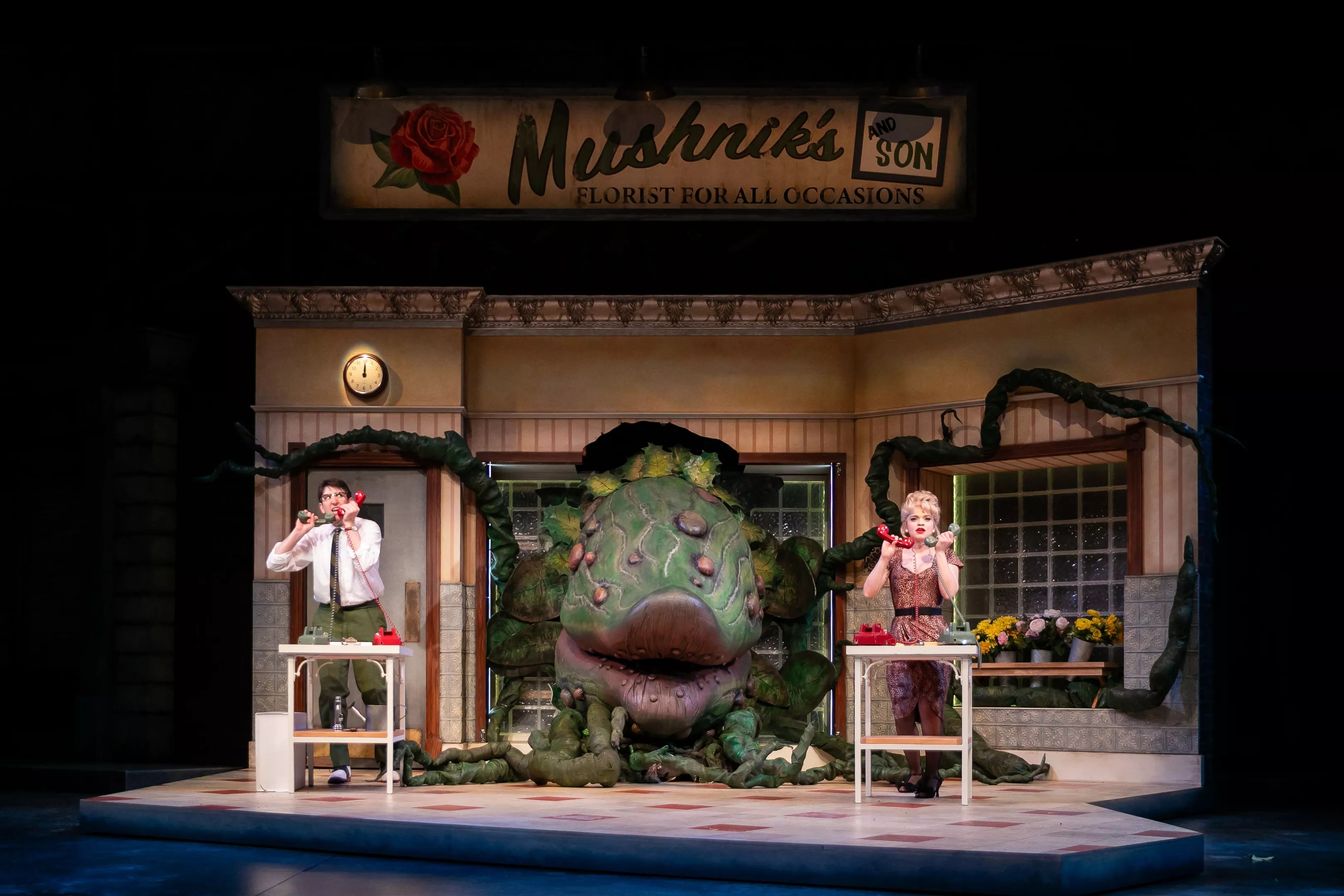 The plant in Little Shop of Horrors looms large inside a flower shop.