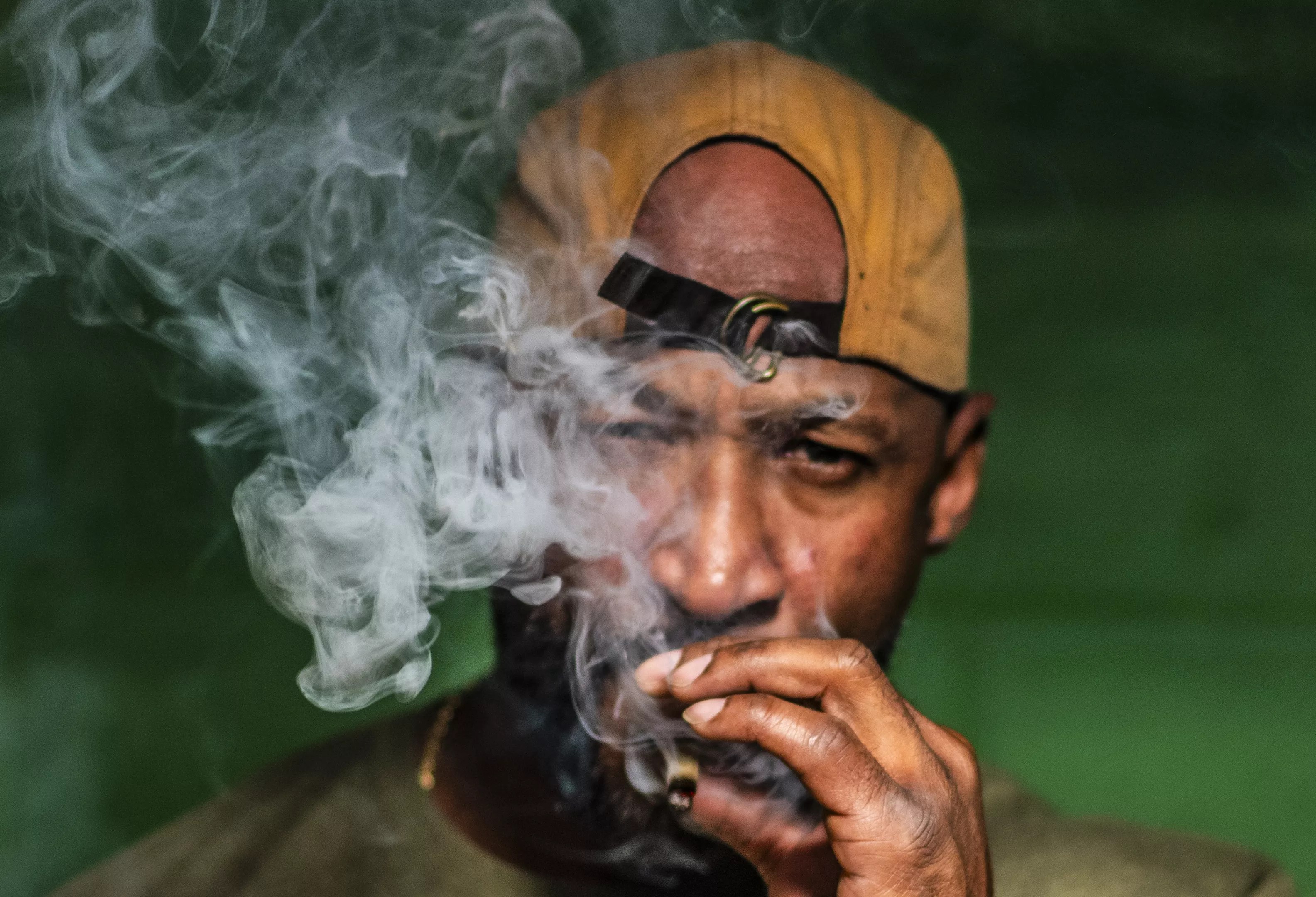 Man with backwards hat smokes joint