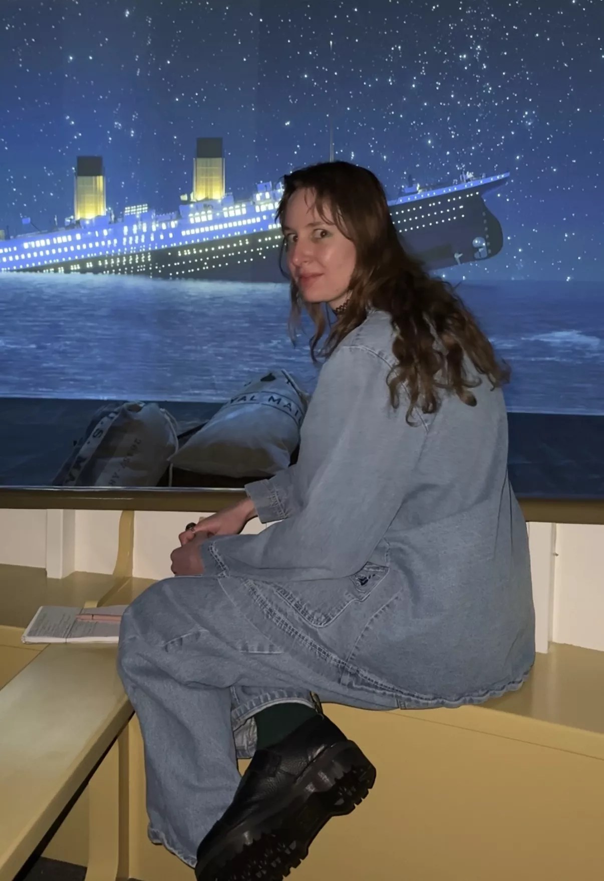 A person sits in front of a screen that displays a rendering of the Titanic sinking.